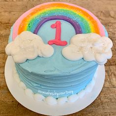 a birthday cake decorated with clouds and a rainbow