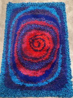 a blue and red rug on the floor with a spiral design in the middle,