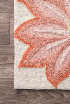 an orange and white flower rug on top of a wooden floor next to a wood floor