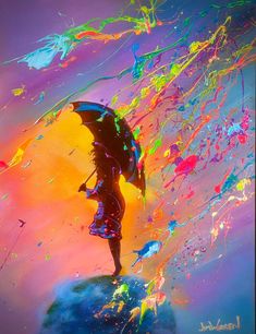 a person holding an umbrella standing on top of a hill with colorful paint all over it