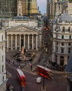 an aerial view of a city street with buildings in the background and two red double decker buses passing by