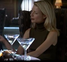 a woman sitting at a table with two martini glasses