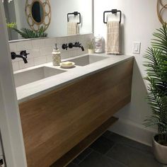 a bathroom sink sitting under a large mirror next to a potted plant in front of it