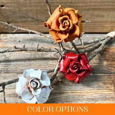 three different colored paper flowers sitting on top of a wooden table next to each other