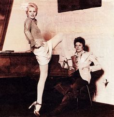 an old photo of two women posing in front of a piano with their legs spread out