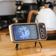 a cell phone sitting on top of a wooden table next to a toaster oven