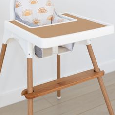 a baby's highchair with a cushion on the seat and wooden legs