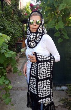 a woman is wearing a black and white crocheted scarf