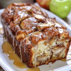 a close up of a cake on a plate with caramel drizzle and apples in the background