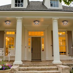 a white house with columns and lights on the front porch