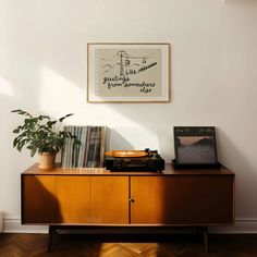 a record player sitting on top of a wooden cabinet next to a potted plant