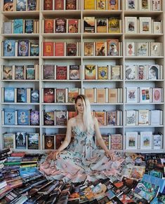 a woman is sitting on the floor in front of a book shelf filled with books