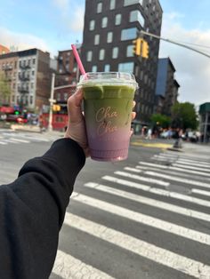 a person holding up a cup with a straw in the middle of a crosswalk