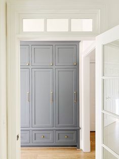 an empty room with gray cabinets and wood floors, along with white trim on the walls