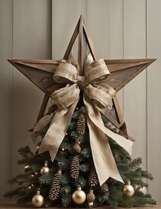 a wooden star decorated with burlocks and pine cones on top of a christmas tree