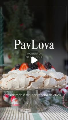 a cake with berries and cream on top sitting on a table next to a christmas tree