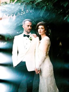 a man in a tuxedo standing next to a woman wearing a wedding dress