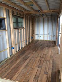 the inside of a shipping container with wood flooring and walls in place for storage