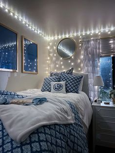 a bedroom decorated in blue and white with lights on the wall above the headboard