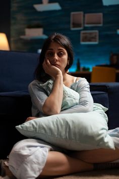 a woman sitting on the floor with her hand under her chin