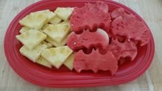 a red plate topped with cut up fruit on top of a wooden table