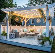 an outdoor living area with couches and lights on the pergolan roof, surrounded by potted plants