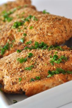 two pieces of chicken with parsley in a white dish