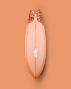 an orange surfboard with red and white designs on the bottom, against a peach background