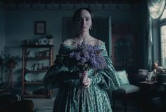 a woman standing in a room holding a bouquet of flowers