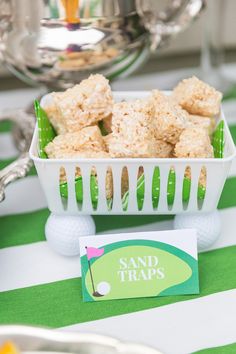 some food is in a white basket on a green and white tablecloth with silverware