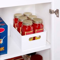 a refrigerator filled with lots of red jars and food in it's drawer next to a carton of pasta