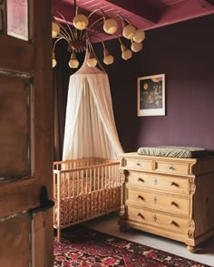 a baby crib and dresser in a room with purple walls