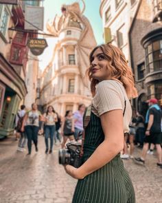 a woman standing in the middle of a street holding a camera