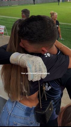 a man and woman embracing each other at a soccer game