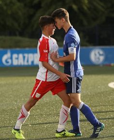 two boys are playing soccer on the field together and one boy is holding his head