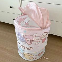 a pink trash can sitting on top of a wooden floor next to a white dresser