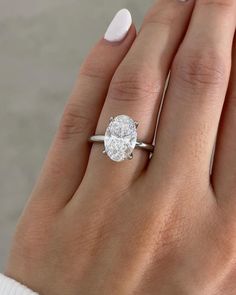 a woman's hand with a diamond ring on her finger and white nail polish