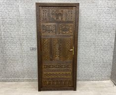 an ornate wooden door in front of a brick wall with white tiles on the floor