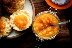 an orange jam in a glass jar next to some biscuits