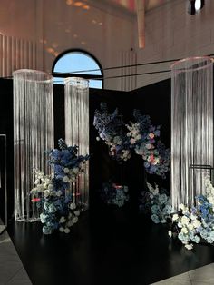 three tall vases filled with blue and white flowers sitting on top of a black table