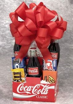 a coca - cola gift basket filled with assorted sodas and chocolates, wrapped in red ribbon