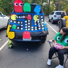 a woman sitting on a chair in front of a car decorated with monster heads and teeth