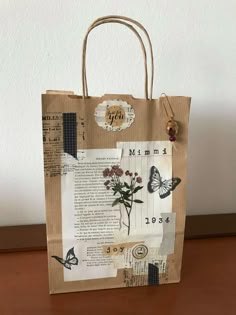 a brown paper bag with flowers and butterflies on it, sitting on top of a wooden table