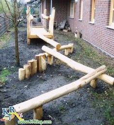 a wooden bench made out of logs in front of a brick building