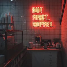 a red neon sign that says but first, coffee on the counter in a dark room