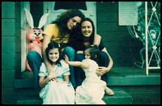 three women and two children are sitting on the front steps of a house with easter decorations