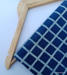 a pair of scissors sitting on top of a piece of blue fabric next to a wooden frame