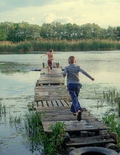 two young boys running across a wooden dock