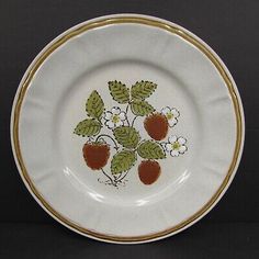 a white plate with strawberries and flowers painted on the side, sitting on a black surface