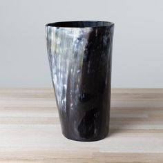 a black vase sitting on top of a wooden table